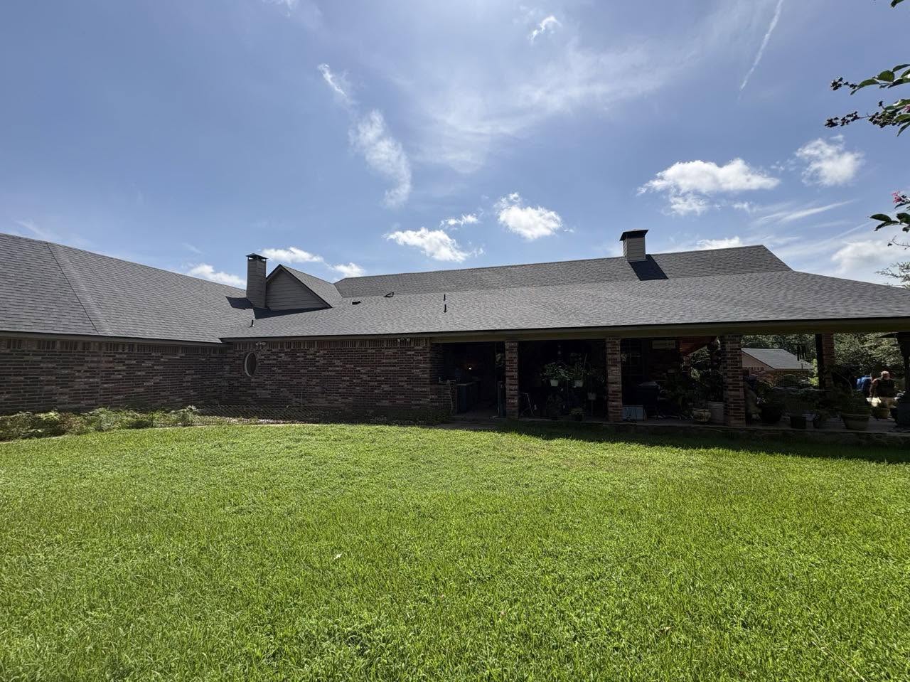New charcoal shingle roof on a Houston brick home with covered patio